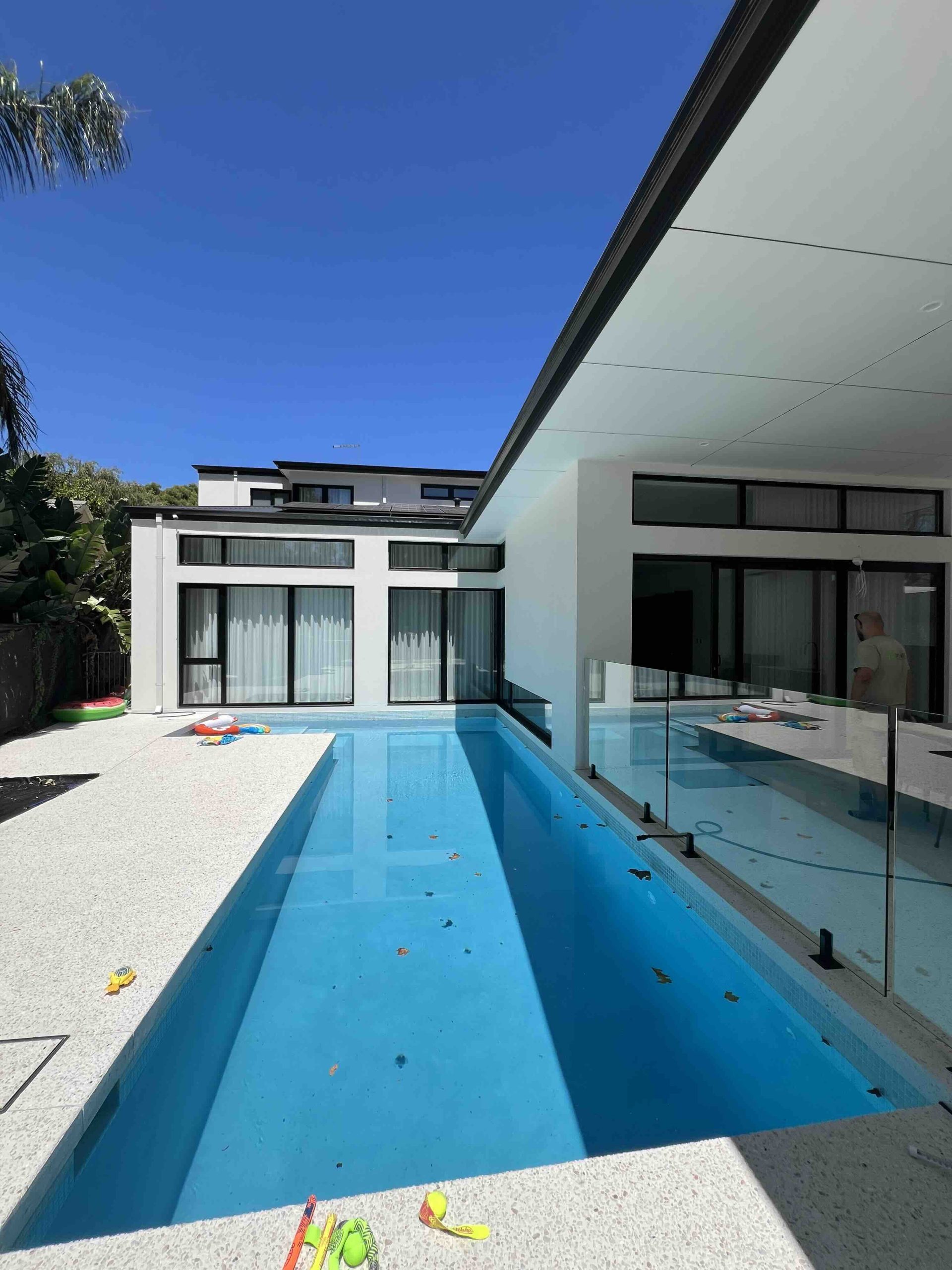 Black thermally broken aluminium sliding doors installed in Perth modern home overlooking pool area by Penot Double Glazing, double glazed for energy efficiency and coastal durability.